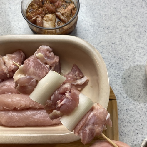 （ネギ間串）串に鶏もも肉、ネギの順でさす。（1串に鶏もも肉3つ、ネギ2つ使用）