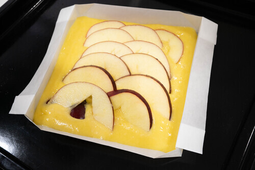 型紙の上に流し入れ、表面を平らにする。②を少し重なるようにして並べる。生地の上にアーモンドスライス、りんごの上にグラニュー糖とバターを散らす。
