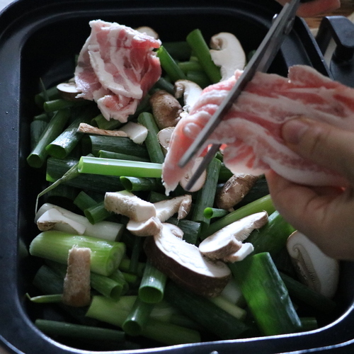 ねぎとしいたけをマルチグリルのキャセロールに入れ、その上に豚バラ薄切り肉を5㎝程の長さに切って乗せる。
キッチンバサミで切りながら乗せると良い。
