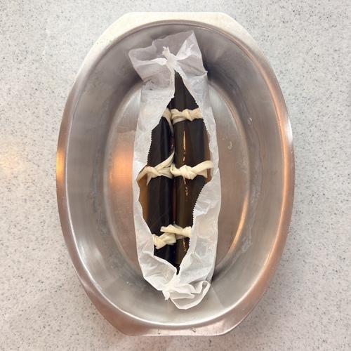 シェフポットにオーブンシートを乗せ、その中に③と＝だし汁＝を半分入れてオーブンシートの端を軽くねじっておく。