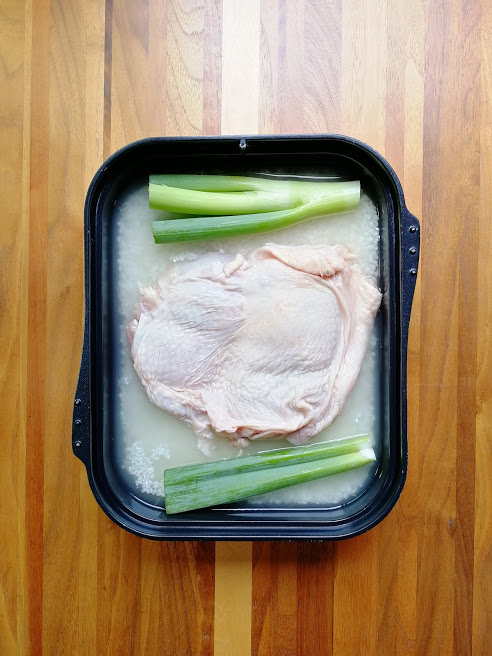 マルチグリルのキャセロールに、米と水分を入れ、鶏もも肉を皮目を上にしてのせ、長ネギの青い部分も乗せる。オートメニュー［ごはん］で炊く。
