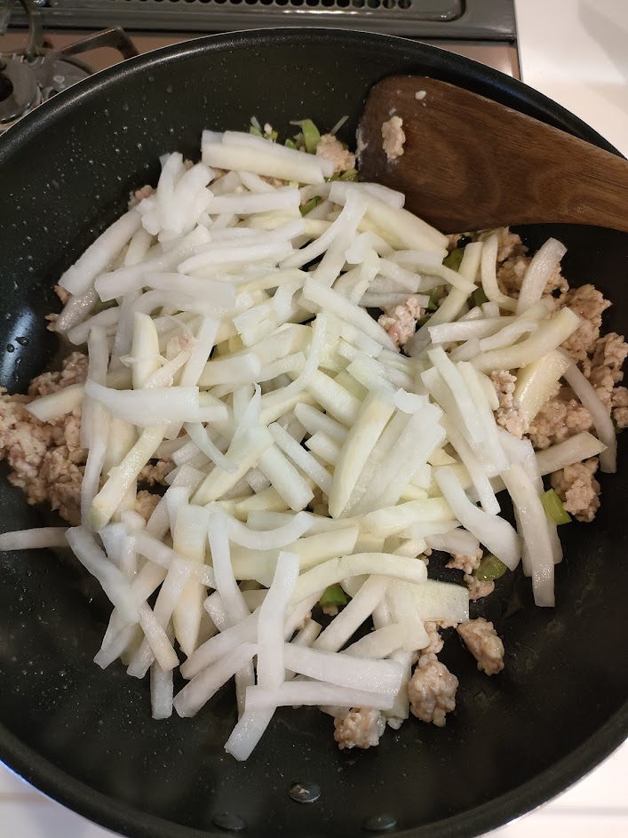 フライパンにごま油を熱し、鶏ひき肉をほぐすように炒める。肉の色が変わってきたら、生姜と大根の葉、③の大根を加えてサッと炒める。