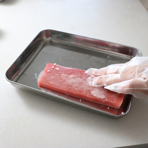 まぐろに塩をすり込み、15分程おいたら出てきた水分を拭き取る。にんにくを薄切りにする。