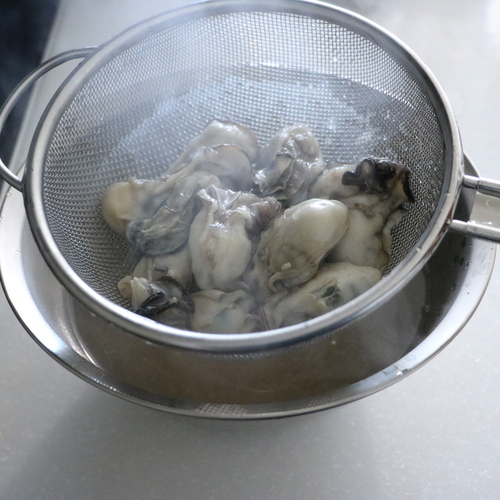 昆布と水の入った鍋に酒を加えて中火にかける。沸騰したら牡蠣を入れ沸騰して2分経ったらざるにあげ、煮汁と牡蠣に分ける。