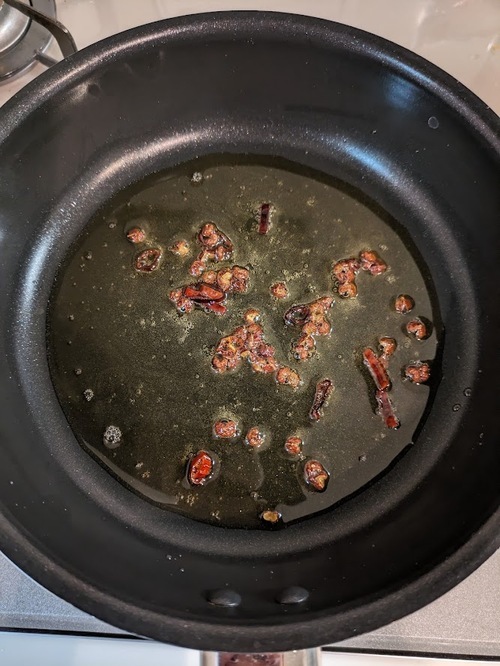 フライパンにごま油と花椒、唐辛子を入れて弱火にかける。焦げないように注意し、香りをだしていく。
