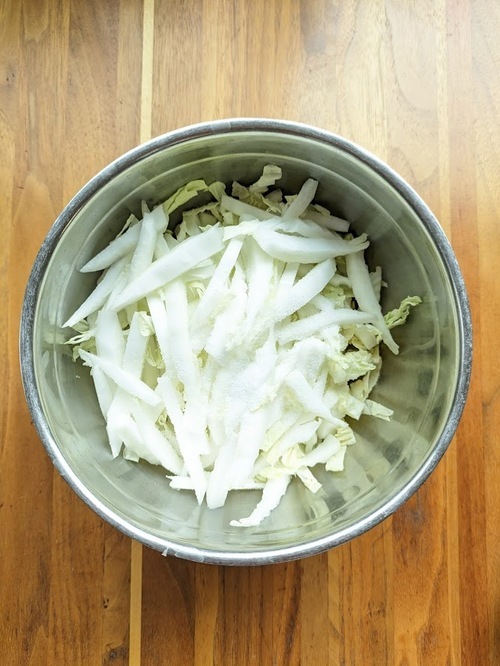 白菜の芯は、繊維に沿って縦に5㎜幅程度に切る。葉も同様。ボウルに入れて塩小さじ1をふって20分おく。

