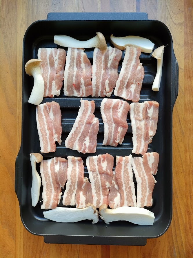 豚バラ肉厚切りは塩をふり、マルチグリルの波型プレートに並べる。空いたスペースにスライスしたエリンギも並べる。