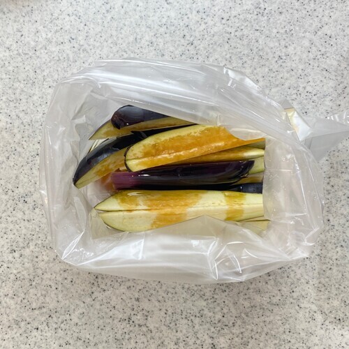 なすはヘタをとり、1本を縦6〜8等分に切ったら食品用ビニールに入れてごま油を回しかける。
