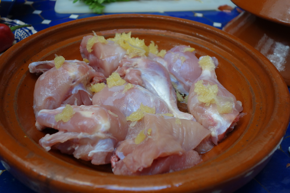チキンを鍋に入れて、レモン汁を絞る。塩漬けレモンの身の部分を手でちぎって加える(皮は残しておく)。