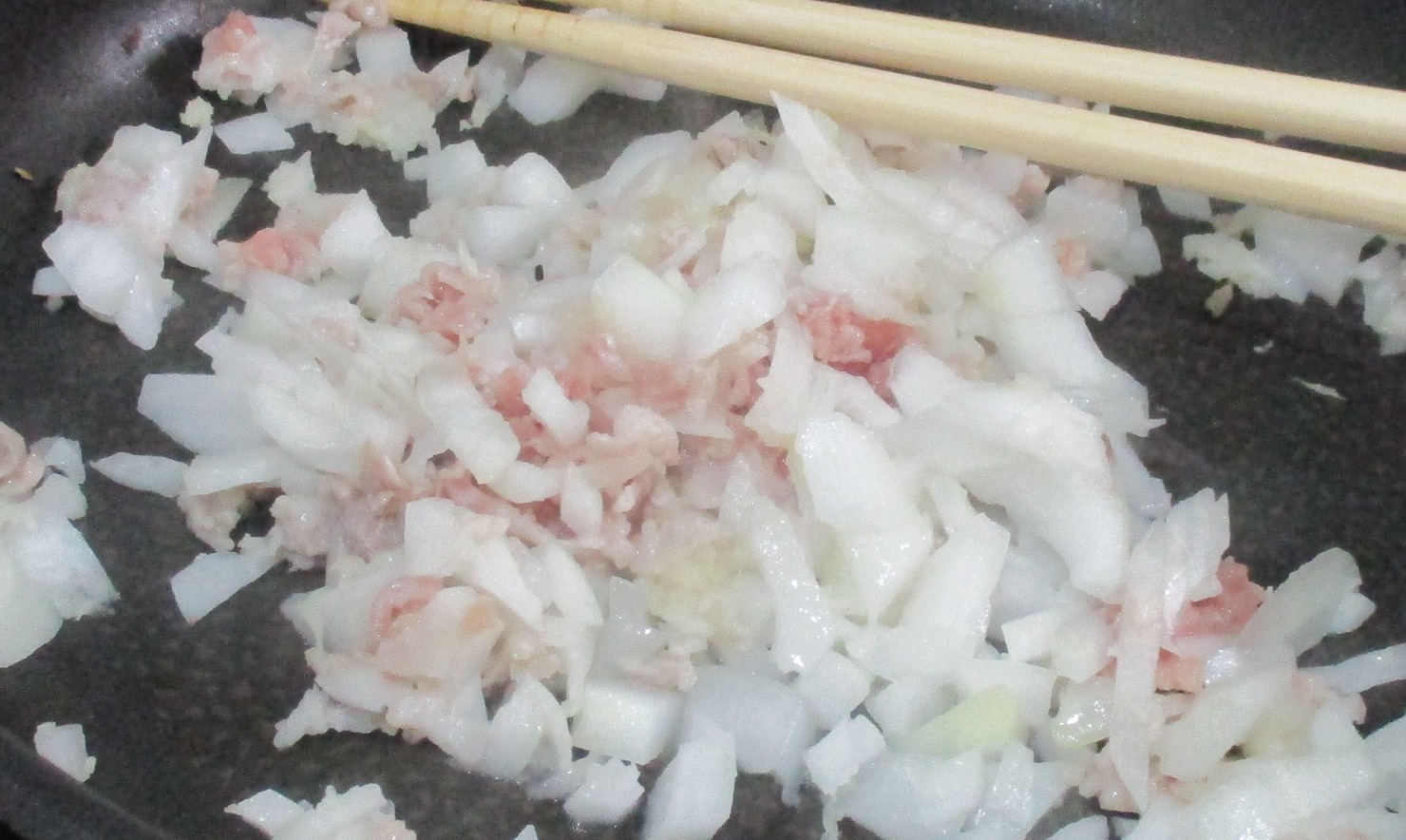 フライパンにごま油を熱し、にんにくのすりおろし、しょうがのすりおろし、たまねぎのあらみじん切り、豚ひき肉を加え、炒め合わせる。