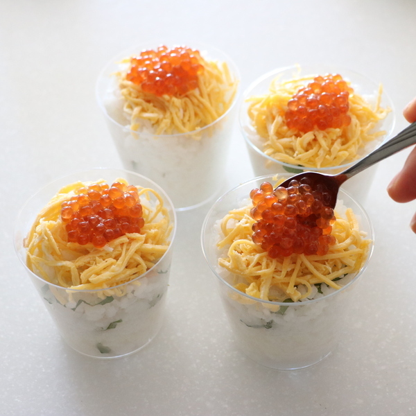 カップにすし飯を入れ、その上に錦糸卵、いくらを乗せ、絹さやを飾る。