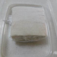 豆腐は、ふきんなどに包み、上から重石をかけ、水切りをよくする。