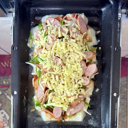 グリルを開け、濡らしたヘラ等で形を整える。
餅が柔らかくなっていたら、ピザソース、ピーマン、玉ねぎ、ハム（またはウインナー）ピザチーズを乗せ、再度上下強火で8分加熱する。
※火傷に注意！
