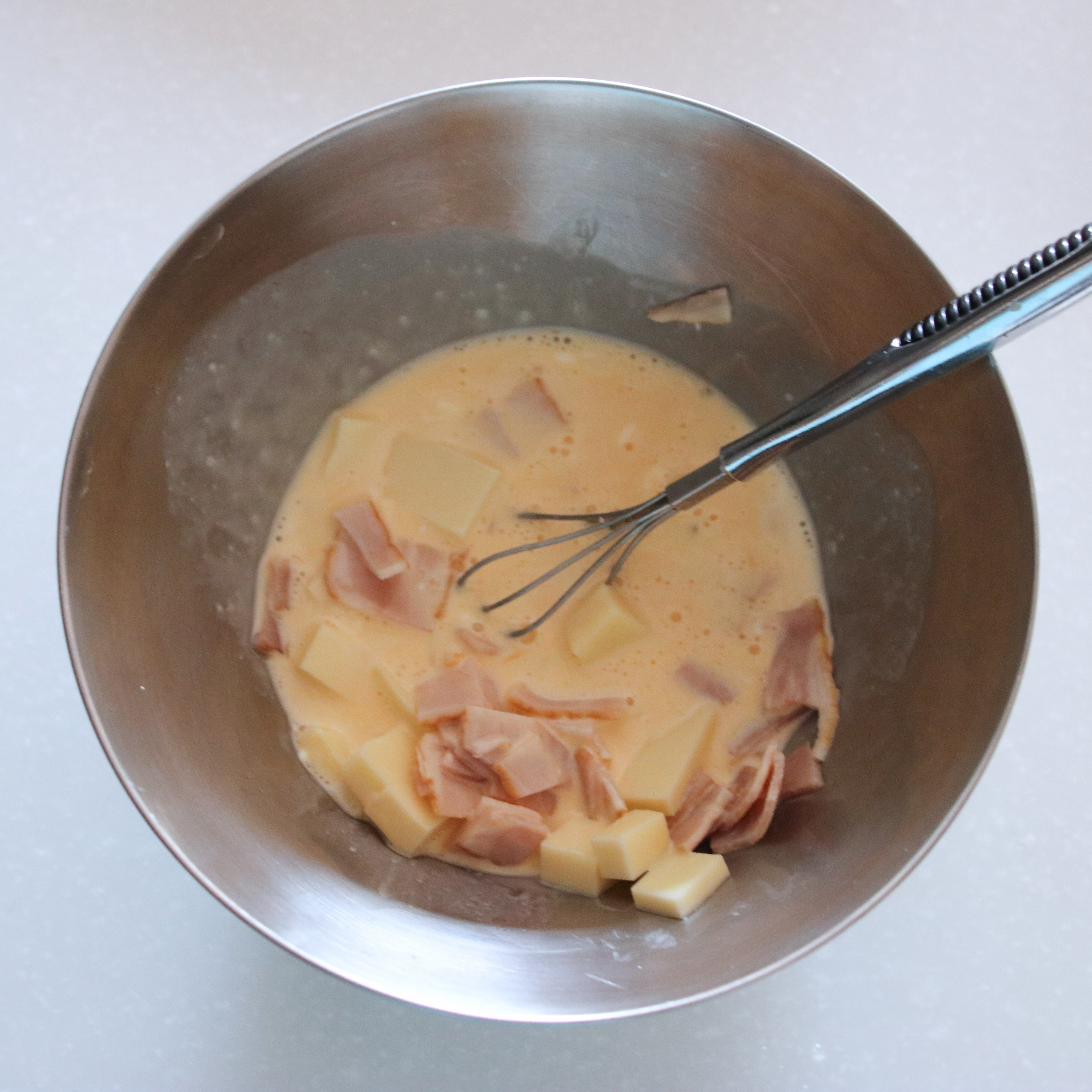 卵をボウルに入れて溶き、生クリーム、塩も加えてよく混ぜたらチーズ、ベーコンも加える。
