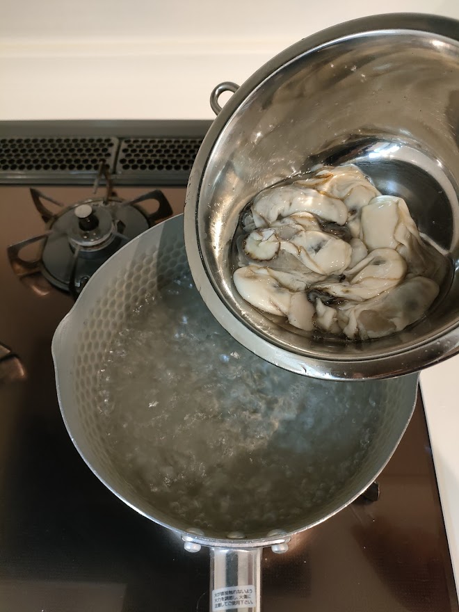 牡蠣は海水程度の塩水（塩は分量外）の中で優しく振り洗いして汚れを取る。熱湯にさっとくぐらせザルにあげておく。