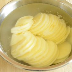じゃが芋は皮と芽を取り除き0.2㎜の厚さにスライスし、水にさらす。ベーコンは1.5cm幅に切る。マッシュルームはスライス、バターを4等分に、パセリは粗みじん切りにする