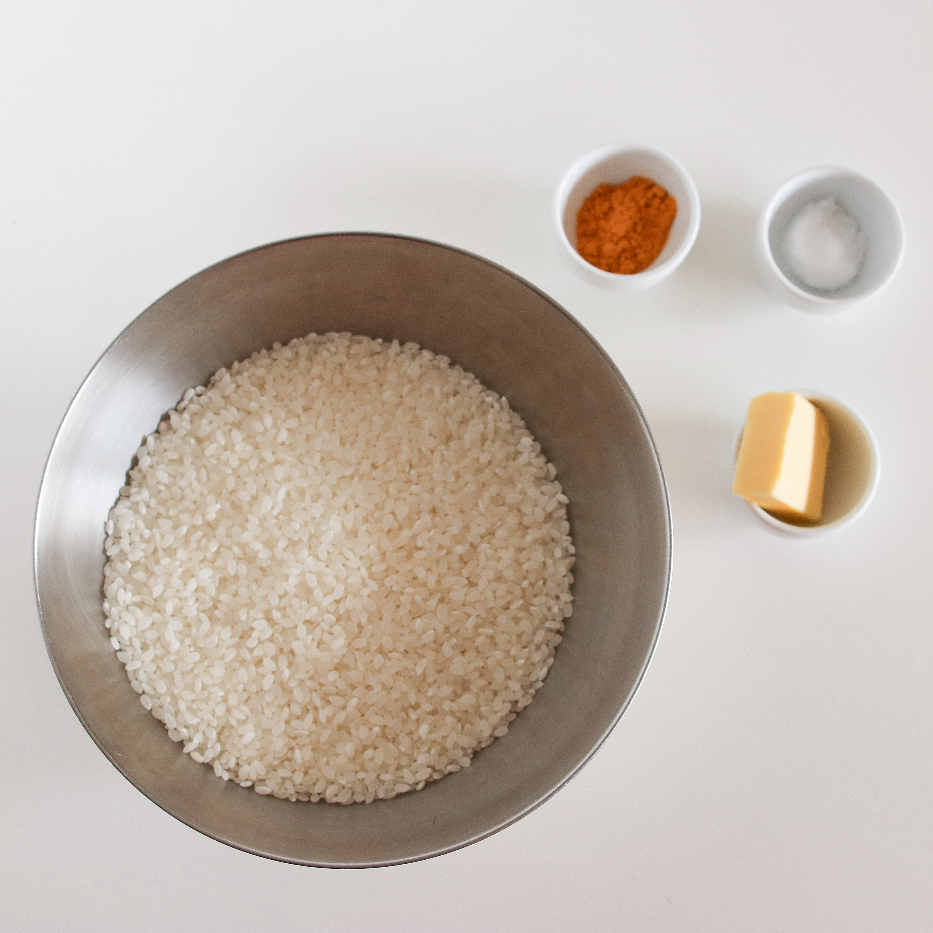 米はさっとといでざるにあげたらすぐにマルチグリルのキャセロールに入れ、水、塩、ターメリックを加えて全体を混ぜる。