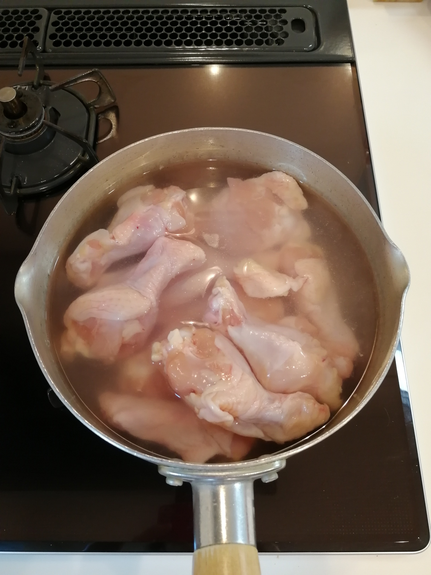 鶏手羽元はドリップが出ていたら水洗いし、鍋に入れかぶるくらいの水を入れて火にかけ、沸騰したら、ザルにあげ、流水でよく洗う。