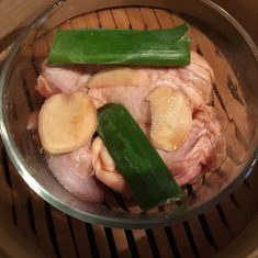 耐熱容器に鶏肉・スライス生姜・ネギを入れ蒸し器に入れて、鶏肉を１０～１５分ほど蒸す。