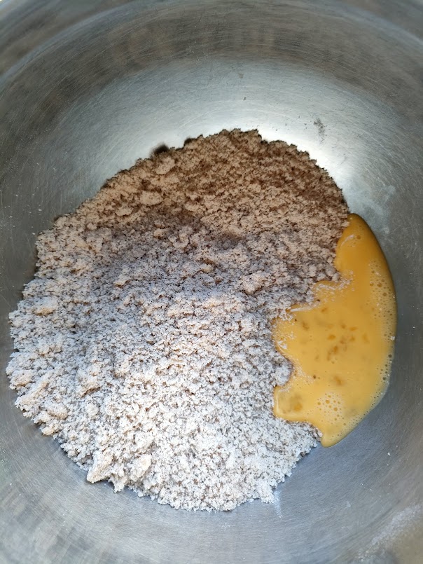 粉類とバターを合わせ、塊を潰すように両手で擦り混ぜる。溶き卵を入れ、ゴムベラで切るように混ぜる。
