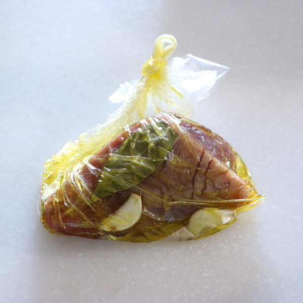 かつおとにんにく、ローリエ、オリーブオイルをポリ袋に入れ、袋の中の空気を抜いて口を縛り、その状態で30分程おく。