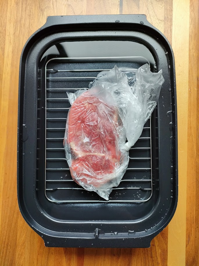 牛もも肉に塩・コショウをし、アイラップに入れる。袋の空気をなるべく抜いて口を縛る。キャセロールに燻製網を入れこみ、肉をのせ、側面段差まで水を加える。