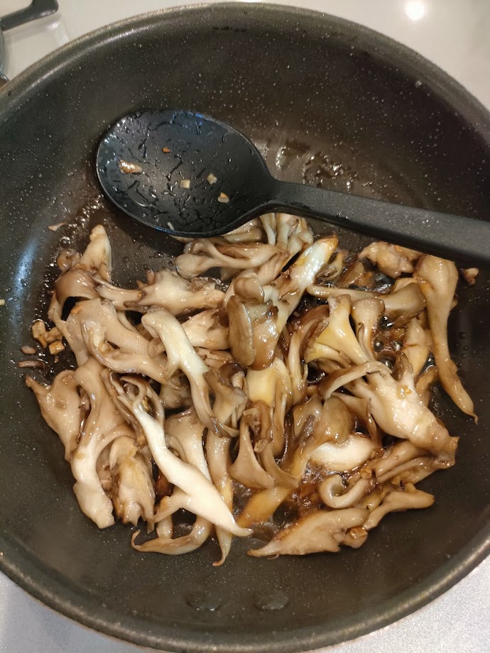 舞茸が炒まったら、醤油を鍋肌から回し入れ、塩コショウで調味する。