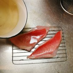 金目鯛は、残っている内臓とうろこを全部取り除いて水道水で良く洗う。80℃程度の湯を満遍なくかけ（霜降りと言う）臭みをとる。