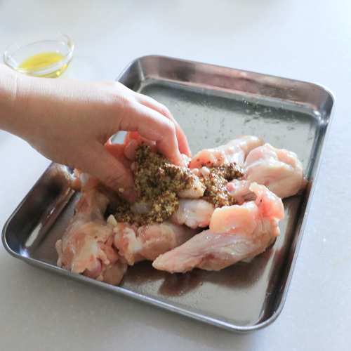 鶏手羽元肉は骨に沿ってキッチンバサミで切り込みを入れ、はちみつと塩をもみこんでマスタードをまぶす。
