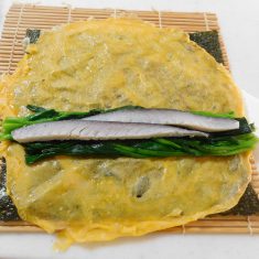 巻きすに、海苔、薄焼き卵、ほうれん草、しめさば、ほうれん草の順に置き、クルッと巻く。(サランラップに巻いてしばらく置いておくと、おちつきます。)