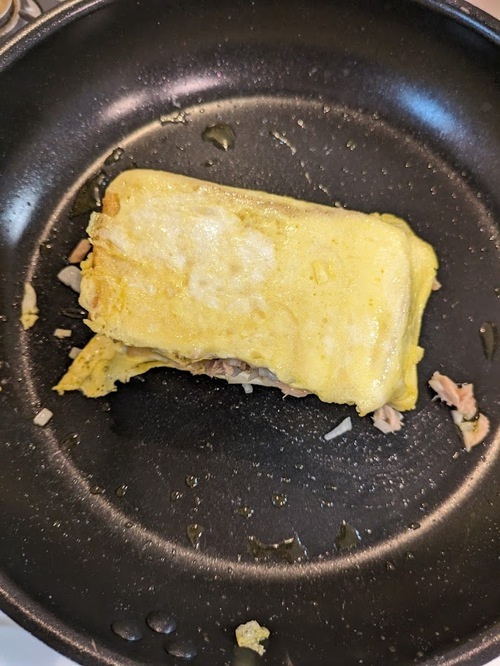 まわりの卵が焼けてきたら、食パンを包むように折りたたむ。パンを重ね、形を整える。バター5ｇを足して、焼いたら完成。
