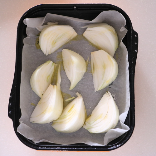 マルチグリルのキャセロールにクッキングシートを敷き、新玉ねぎを並べたらオリーブオイルと塩を全体にかける。