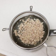 鶏肉をざるに入れ、熱湯に入れて菜箸でほぐし、熱が入りきる前に取り出しておく。