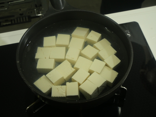 豆腐を２ｃｍ角に切り、鍋にいれ、豆腐が浸かるくらい水（分量外）を注ぐ。中火にかけ、沸騰したら、ザルにあけ水気をきる。
