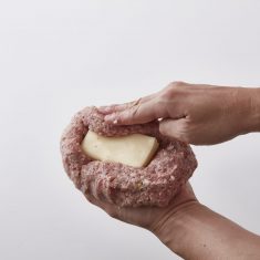 ②にたまねぎ、卵、パン粉、牛乳をいれ揉みながらよく混ぜる。袋から取り出し真ん中にくぼみをあけ、①のチーズをのせ、包み、１６ｃｍ×１４ｃｍのハンバーグの形にする。
