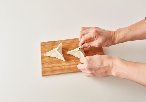 餃子の皮の中央に２をのせ、皮の縁に水をぬる。
皮を三方向から持ち上げて中央で合わせ、縁をしっかりと留める。