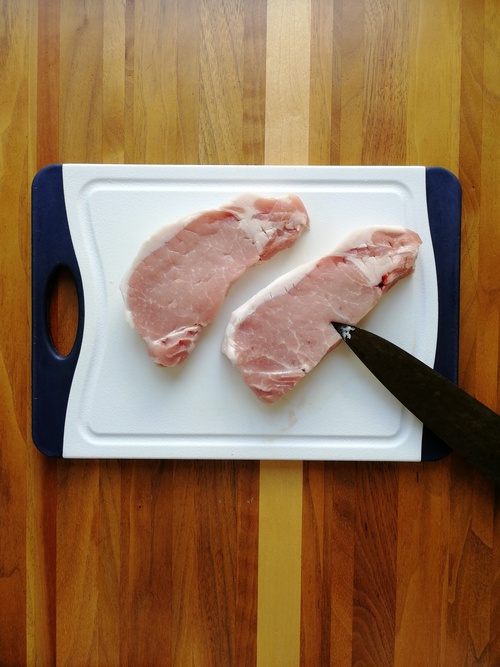 豚ロース肉は脂身と赤身の間に数か所、包丁の先で切れ目を入れる（筋切り）。赤身部分にも繊維に垂直に何か所か包丁の先でツンツンと刺しておく。