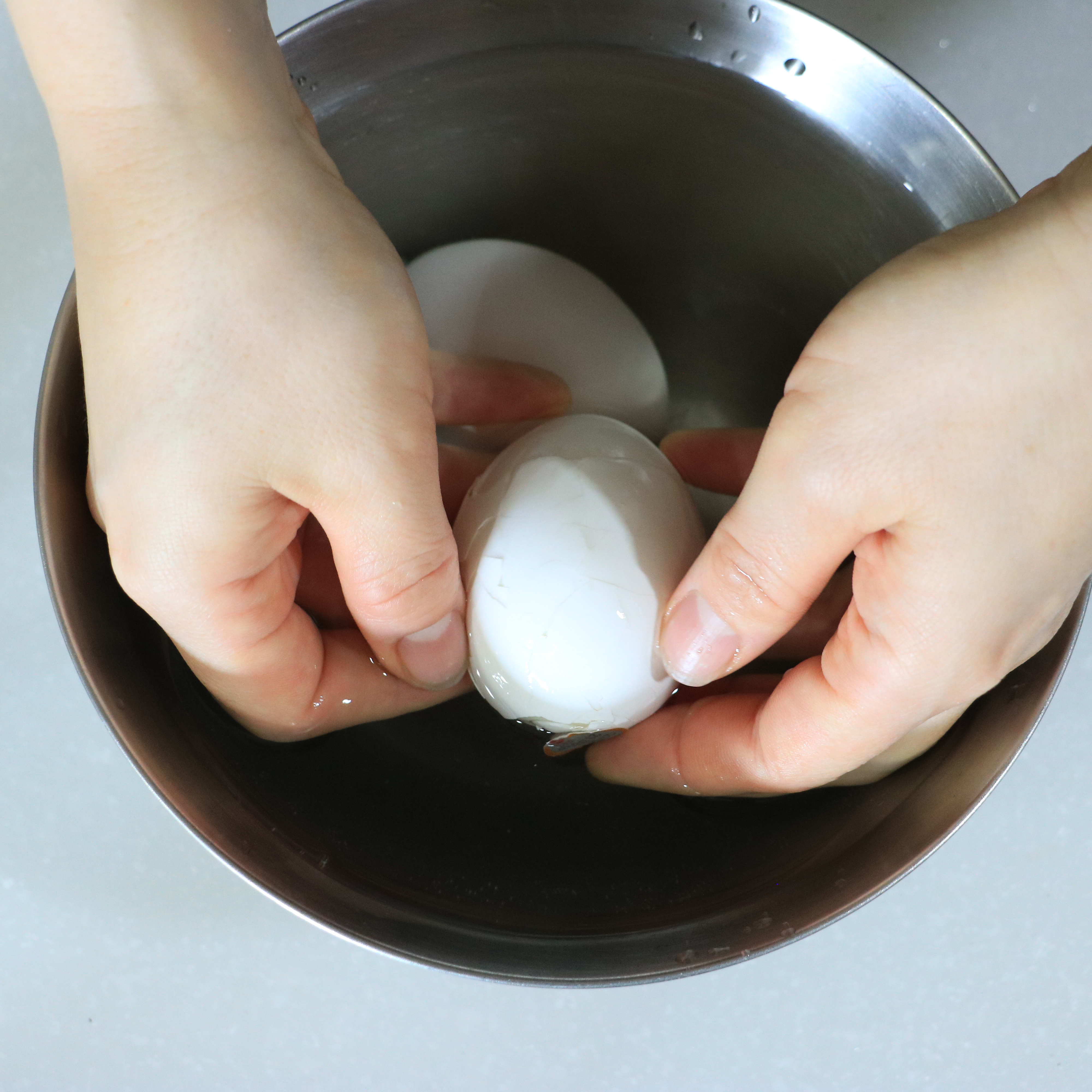 卵を取り出し氷水の入ったボウルに入れる。卵が冷えたら全体にひびを入れ、水の中でからをむく。むいた卵は水気をしっかりふき取る。