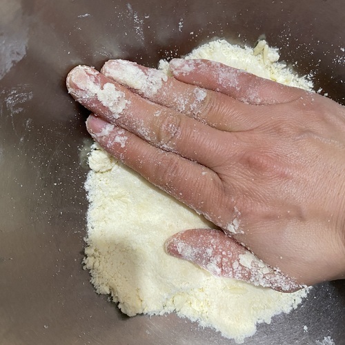 手でボウルに押し付けるようにして粉類にバターを馴染ませる。