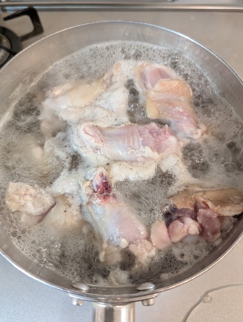 鶏手羽元を鍋に入れひたひたになるまで水を注ぎ、火にかけて一度茹でこぼす。
水洗いして汚れを洗い流し、水気を切っておく。