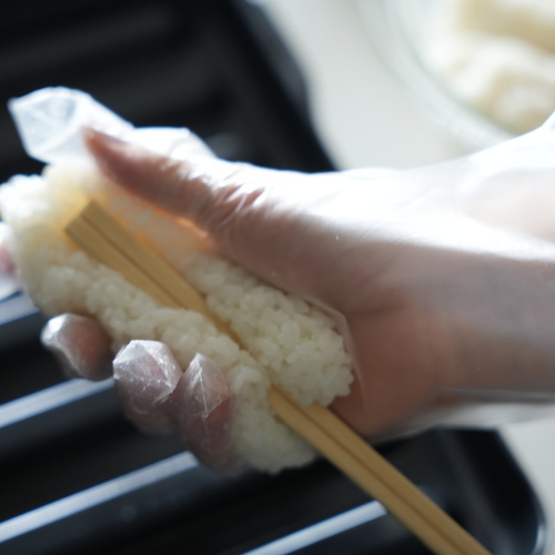 温かいご飯をボウルに入れ、すりこぎで米をつぶす。
米を4等分し、割りばしの太い方にぎゅっと押し付けるようにつけ、小判型に整える。