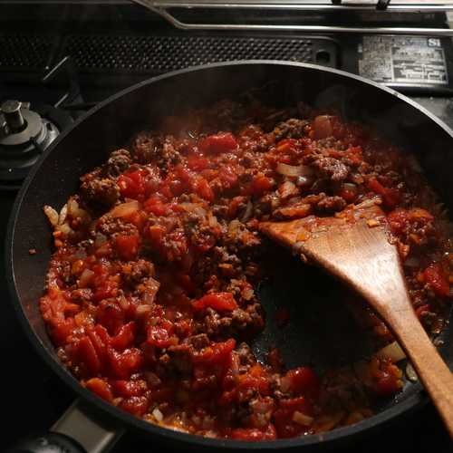 合いびき肉も入れて炒め、肉にしっかり火が通ったらトマトホール缶を潰して入れる。顆粒コンソメと塩も加えて、水分が飛ぶまで5分程煮る。
