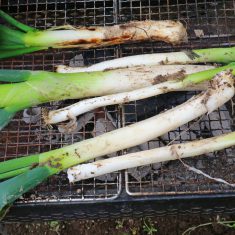 岩津ねぎの根っこを取り除き、泥付きのまま切らずにそのまま網にのせて焼く。家庭で作る場合は、ガスコンロのグリルを使用。コンロに入る長さに切って中火で、中まで火が通るまで焼く。