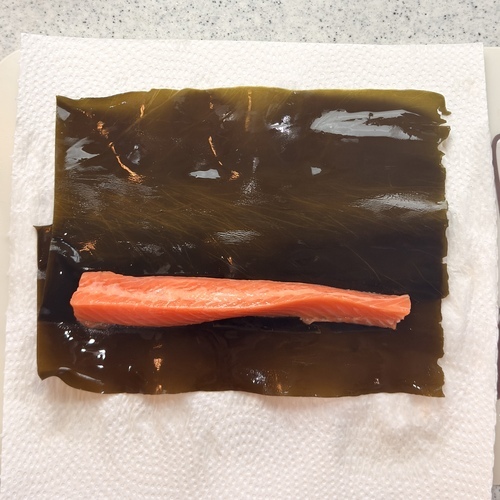 昆布の水気を拭き、昆布を横長に、少し重ねながら置く。
 サーモンを手前に乗せる。