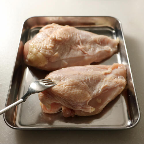 鶏むね肉は皮目にフォークで穴を開けたら4つに切り分ける。しょうがとにんにくはすりおろす。