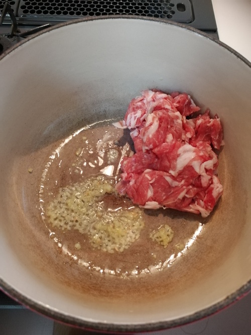鍋に油と生姜を入れ火にかける。香りがしてきたら肉を入れほぐすように炒める。