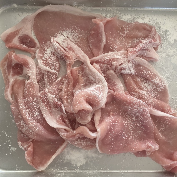 バットに薄力粉を広げ豚肉全体に薄くまぶす。