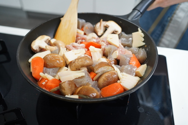 フライパンにゴマ油、鶏肉、たけのこ、にんじん、しいたけ、こんにゃくをいれ、中火にかけ、炒める。