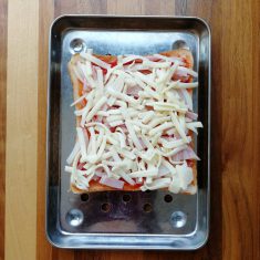 食パンにケチャップを満遍なくぬり、スライスした玉ねぎとハムをのせ、ピザ用チーズを平らに敷き詰める。