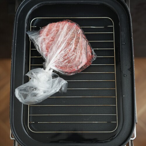 冷蔵庫から出したばかりのステーキ肉に塩こしょうをし、耐熱ポリ袋に入れる。
マルチフリルのキャセロールに燻製網を入れ、肉の入った袋を燻製網の上に置き、側面段差まで水を加える。
フタをして調理モード［低温調理］の中で13分加熱する。
